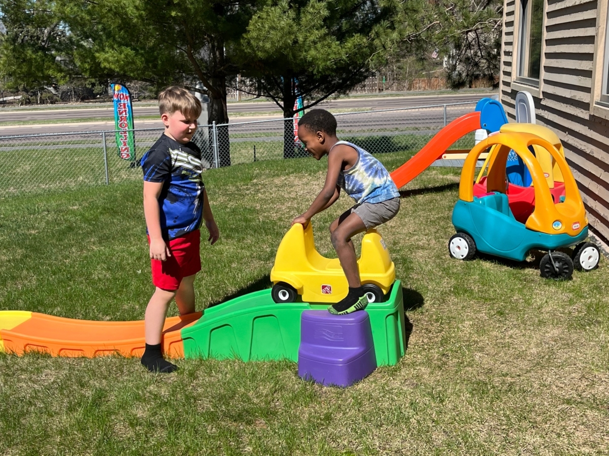 two young boys play with outdoor toys