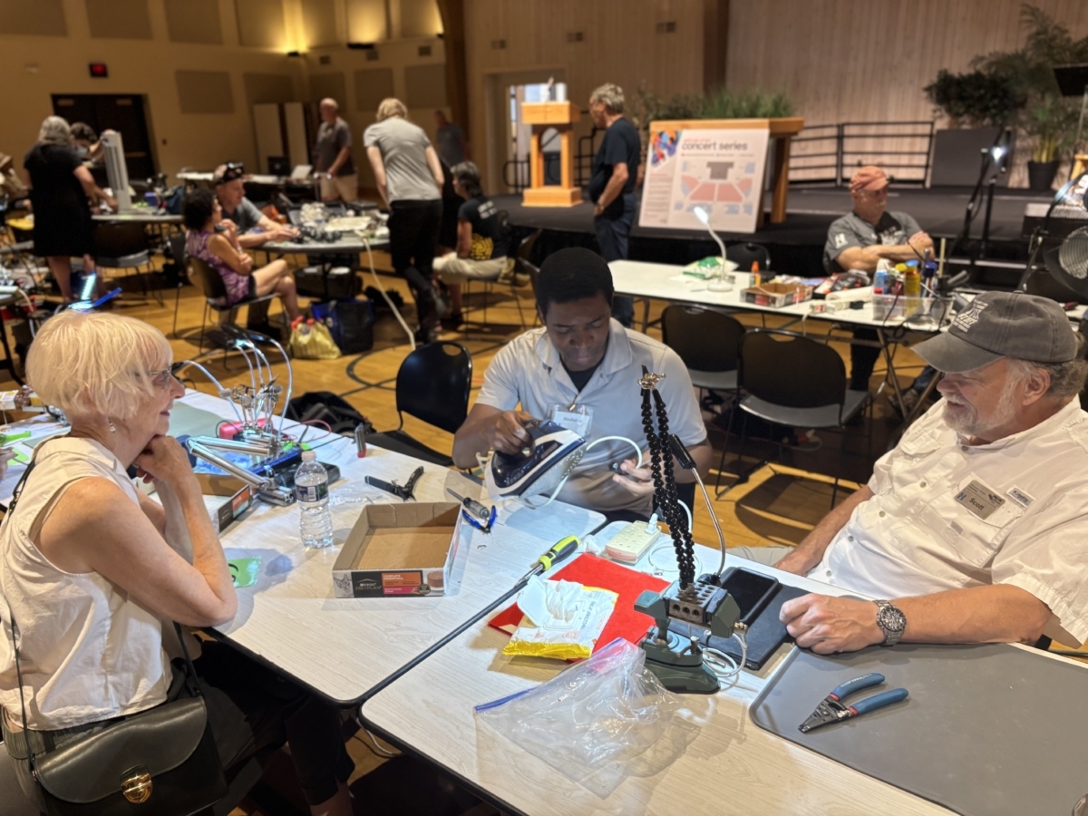 Fix-It Clinic volunteers Abubakar Munir, center, and Scott Olson, right, help diagnose a malfunctioning iron for a customer, left, during a recent clinic.
Photos by Jody Carey