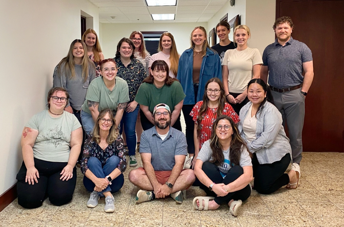 several people pose for a group photo in an interior hallway