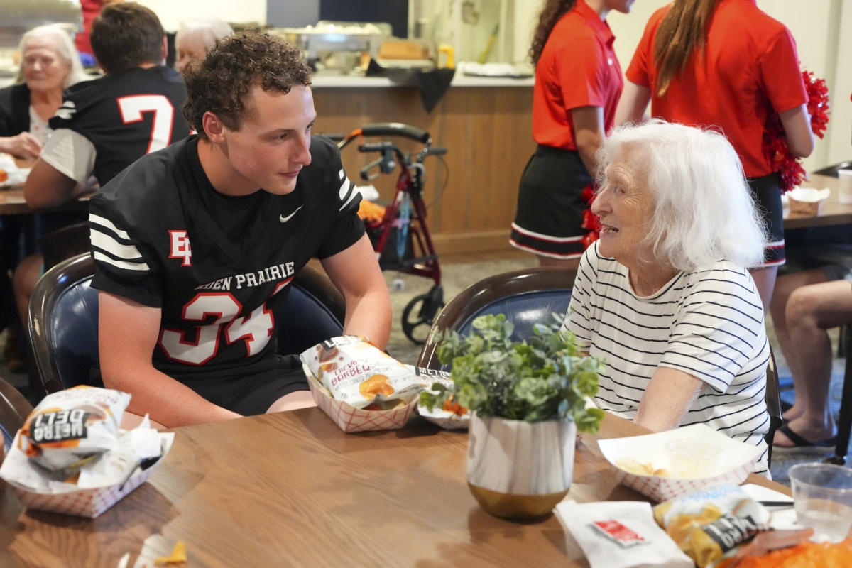 Eden Prairie High School football player Will Kukla (34) visits with The Waters resident Nedra during the Eagles’ 16th annual trip to the senior living community on Friday, Aug. 15. Photo by Rick Olson