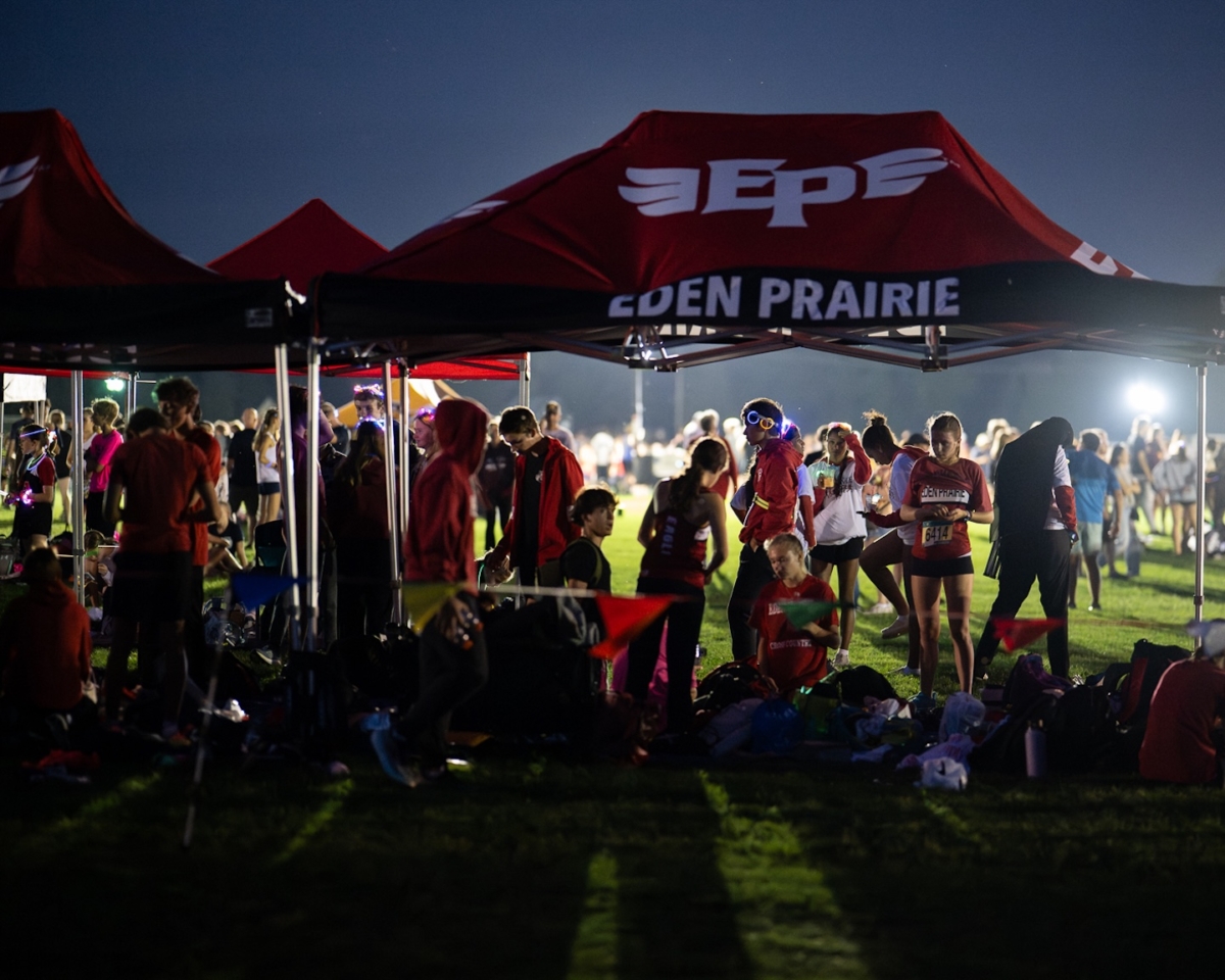 Eden Prairie runners gather under team tents as night falls at the Metro Invitational on Sept. 13 at Flying Cloud Fields. The annual meet, Minnesota’s largest, drew more than 2,000 athletes and featured races under the lights.