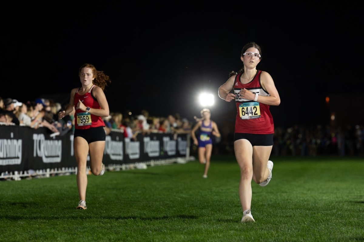 den Prairie’s Briann Peterson (right) runs alongside another competitor during the Metro Invitational on Sept. 13 at Flying Cloud Fields. Peterson placed 15th in the varsity girls’ 5,000-meter race at the meet, which drew more than 2,000 athletes under the lights.