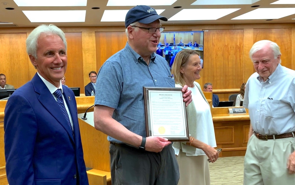 From left: Mayor Ron Case; Steve Schewe, holding a proclamation declaring Sept. 2, 2025, as Steve Schewe Day; Nancy Tyra-Lukens, chair of the Eden Prairie Local News board and a former mayor; and Dean Edstrom, a retired founding board member, during Tuesday’s City Council meeting. Photo by Jeff Strate