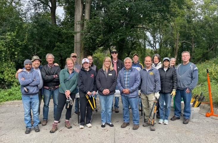 group of people with gardening implements stand in front of trees