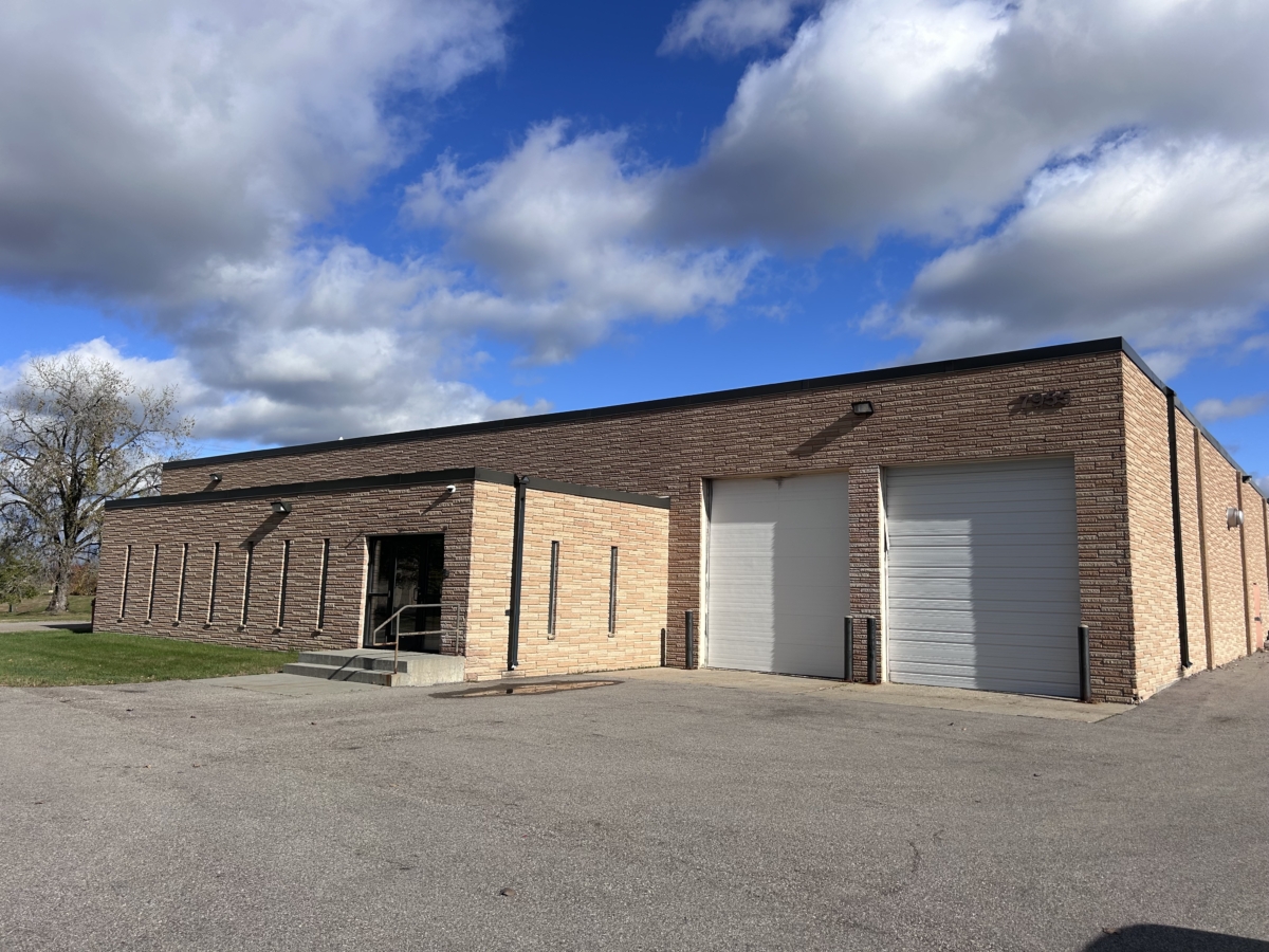 A light brown brick building with two white garage doors.