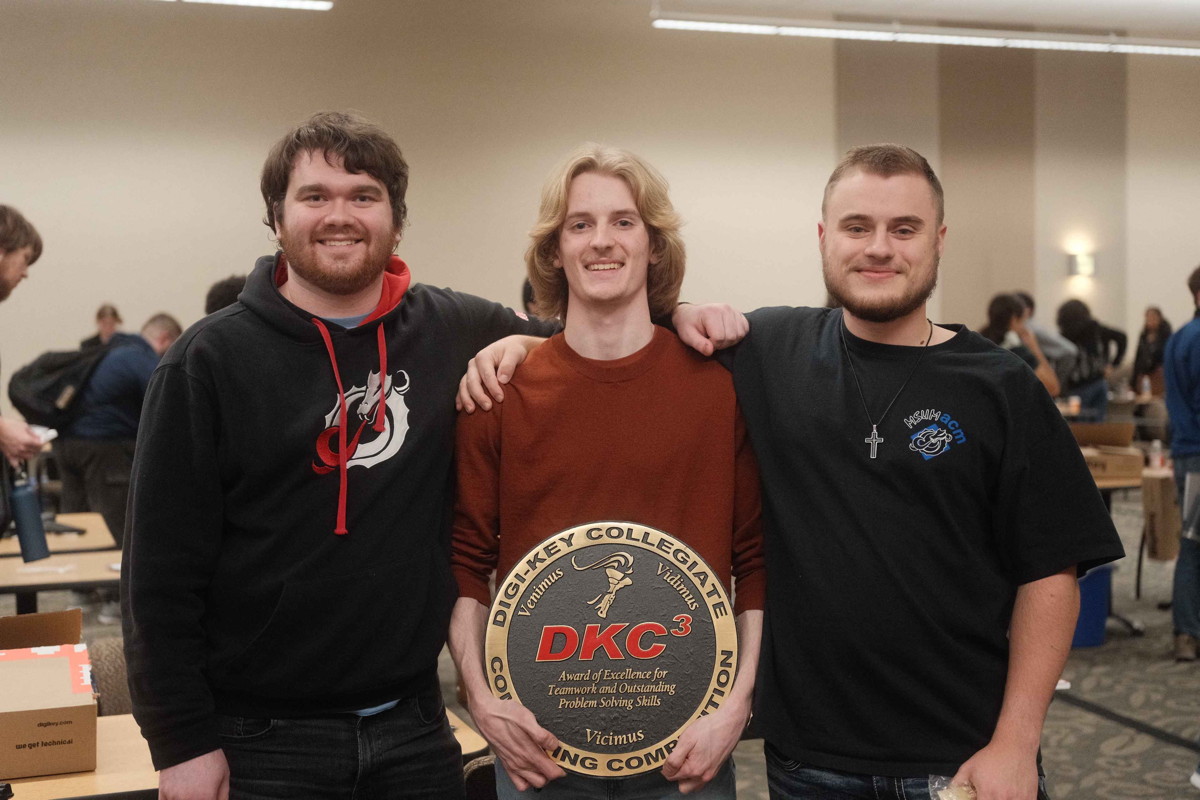 3 young men pose with large round award