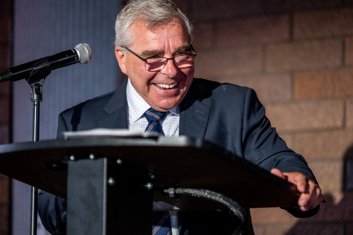 Sen. Steve Cwodzinski laughing. He is standing at a podium and is wearing a suit.
