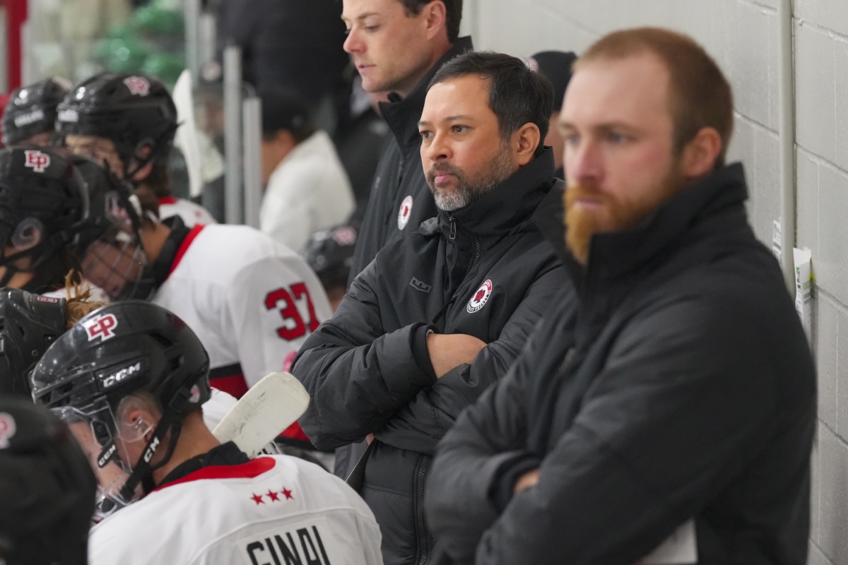 Eden Prairie head boys hockey coach Lincoln Nguyen watches from the bench, with assistant coaches Dan Molenaar and Luc Gerdes beside him.