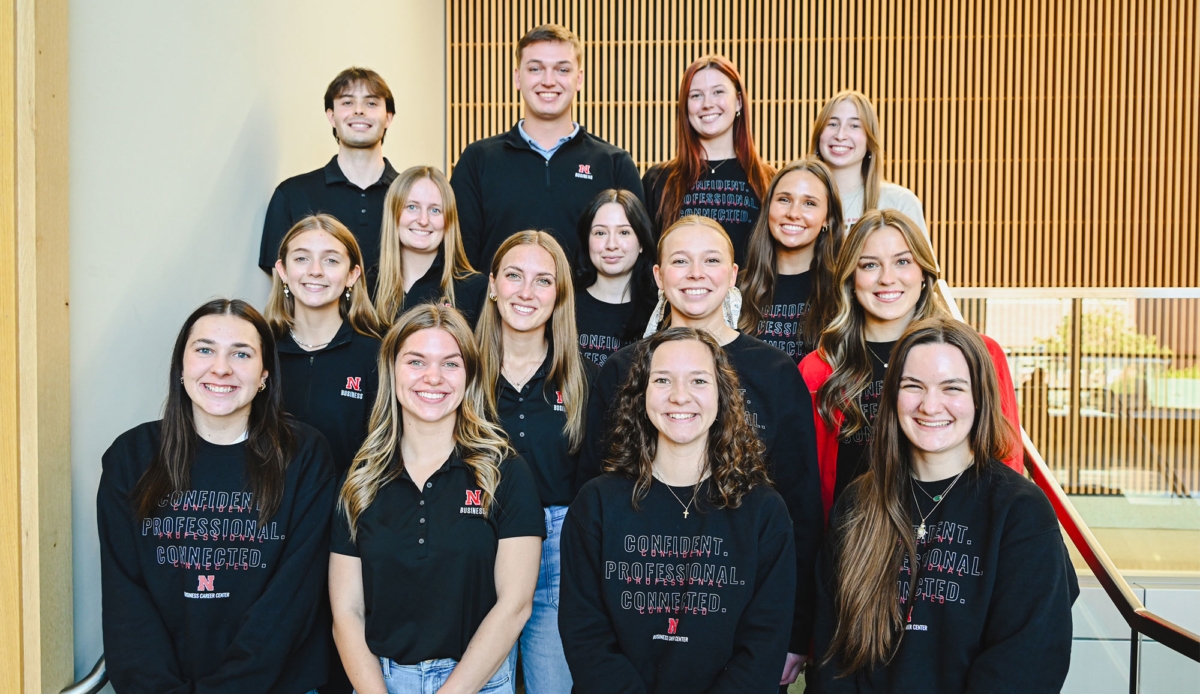 group of young people in black shirts smile and pose for a photo