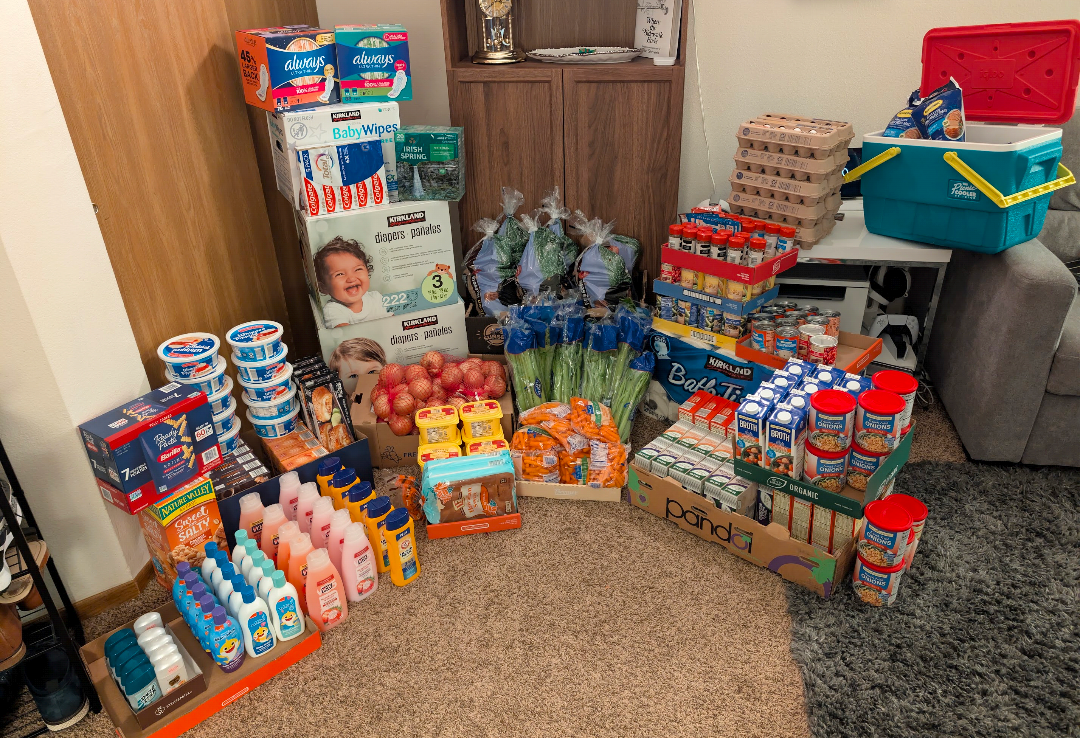 A large collection of Thanksgiving meal ingredients, shampoo, sanitary pads and diapers sit in a carpeted living room.