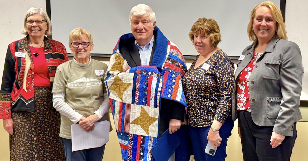 Vietnam veteran Glenn Horton stands wrapped in a patriotic Quilt of Valor, surrounded by Lake Minnetonka DAR Chapter members Karen Wojahn, Margie Nash, and Regent Michelle White during the chapter’s meeting in Eden Prairie.