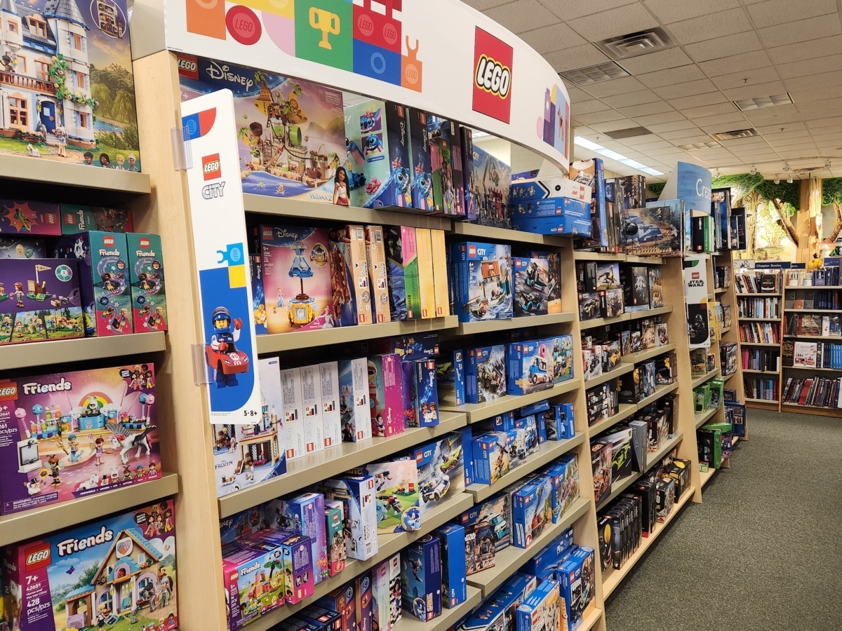 An aisle at a store with the shelves full of Lego kits.
