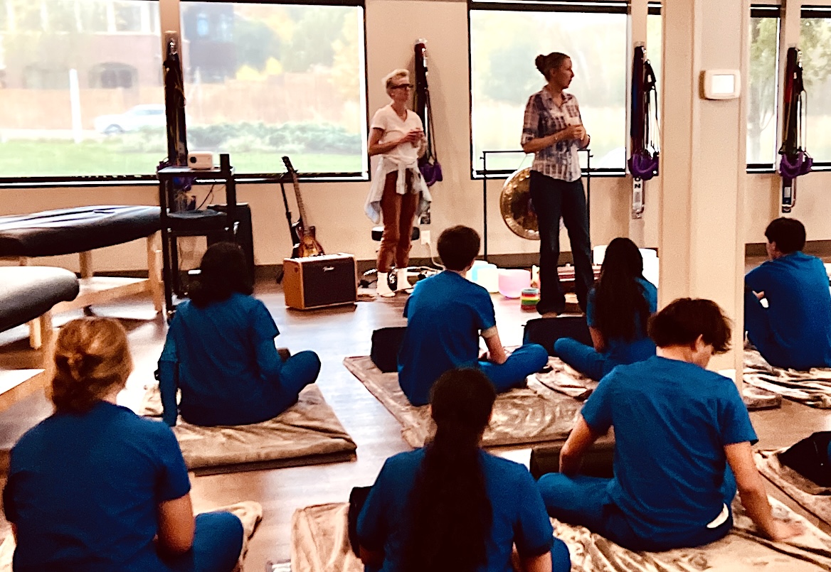 Sound-healing artist Kristin Wertenberger, left, and Wellspring Health Center co-founder Lisa Smith, right, welcome Eden Prairie High School students to a sound bath session. Photo by Rachel Engstrom