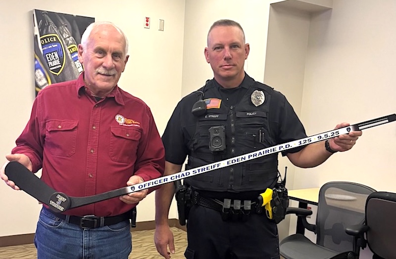 Officer Chad Streiff receives a personalized hockey stick from Bill Hammes honoring his three DWI arrests during a Sept. 5-6 shift.